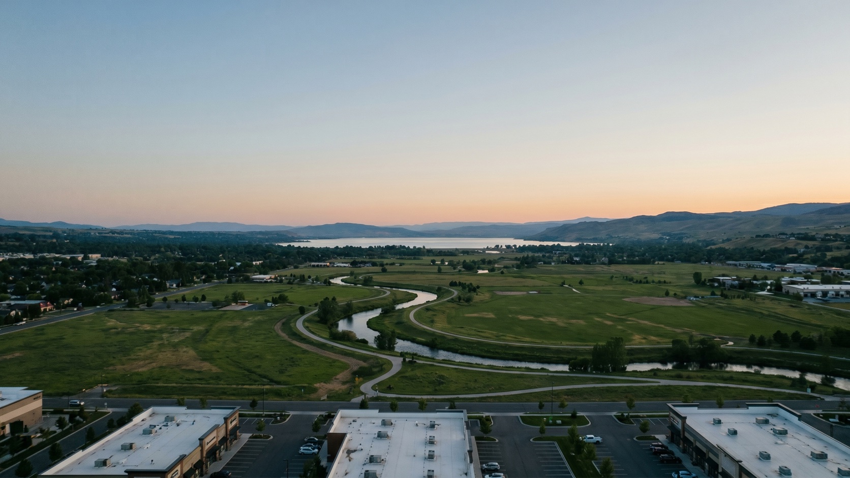 Elevated dusk view over the Sammamish River valley and Redmond commercial corridors with the Cascade foothills beyond